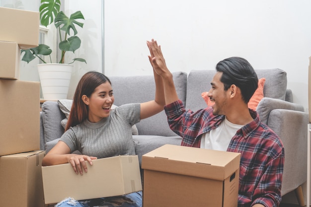 Woman and man unpacking messy boxes after moving in new house together.