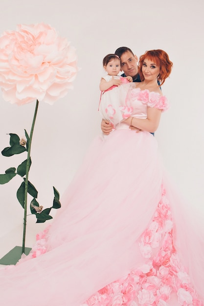 A woman and man with a child in her arms with big flower