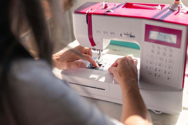 Woman manipulating sewing machine to set the threads