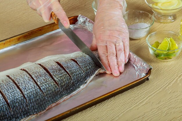 Woman marinated fillet fish cooking raw fish on kitchen onion dish in the oven