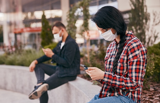 Woman in mask using smartphone in queue