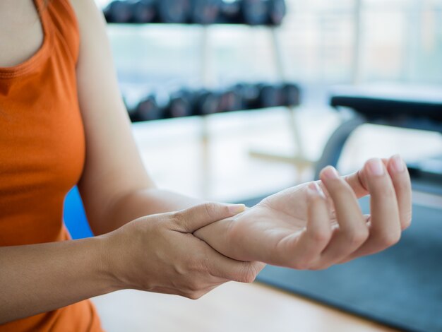 Photo woman massaging her wrist after working out or injured hand during careless sport practice.