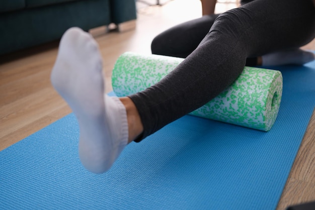 Woman massaging leg with foam roller closeup