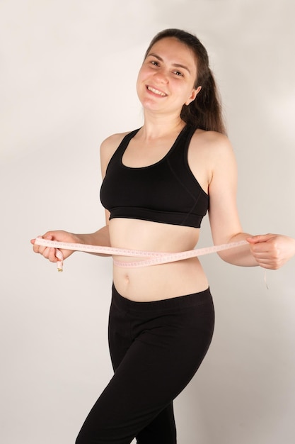 A woman measures the circumference of the abdomen with a centimeter tape