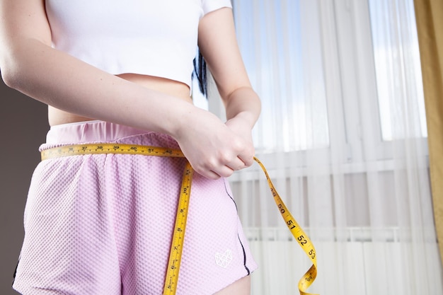 Woman measuring her waist with a measuring tape