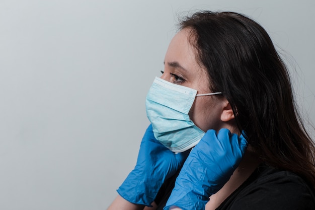 woman in medical gloves puts on a protective mask