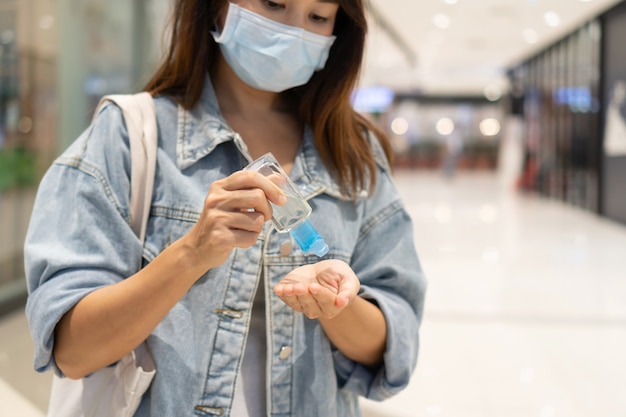 woman in medical mask applying hand sanitizer gel to disinfection and cleaning her hands