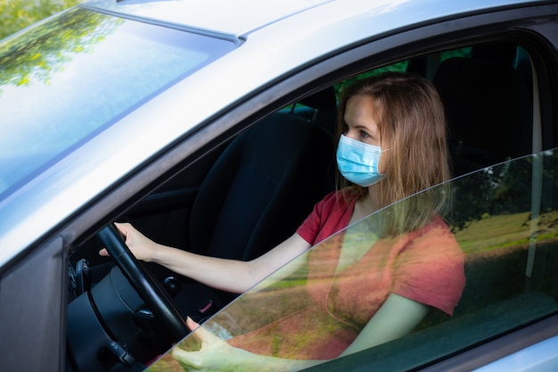 Photo woman in medical mask is driving the car. coronavirus time. dangerous situation.