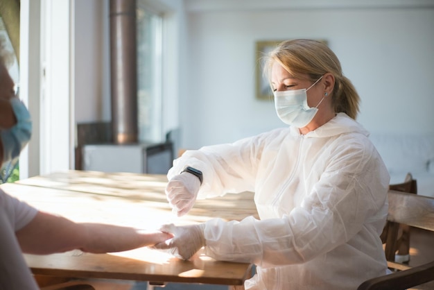 A woman in a medical mask is getting a blood sample from a woman.