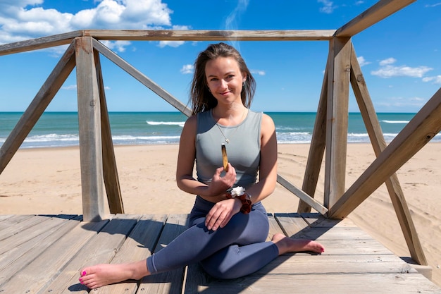 Woman meditating by the beach with a palo santo stick