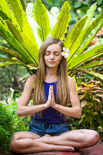 Woman meditating in the tropical garden