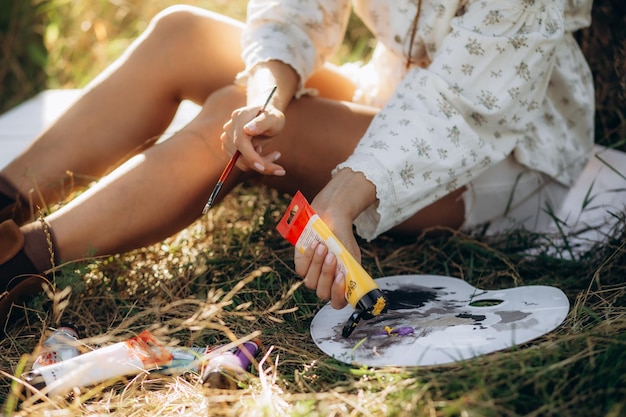 Photo a woman mixes paints on a palette while sitting in nature