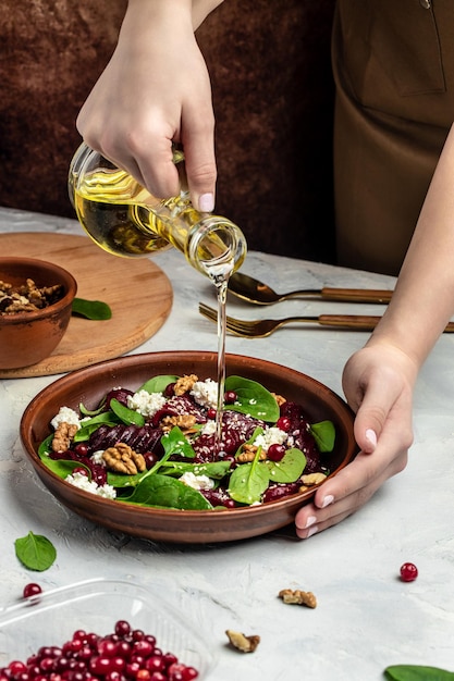 Woman mixing delicious superfood salad with beet fresh baby spinach cheese nuts cranberries Clean eating dieting vegan food concept Food recipe background Close up