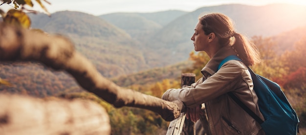 Woman on mountain standing by the fence and enjoying view