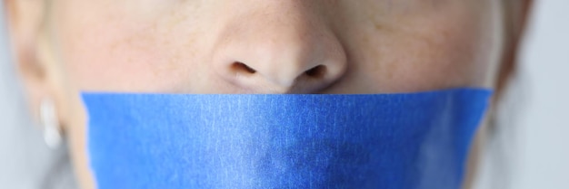 Woman mouth is sealed with blue tape silence and domestic violence concept