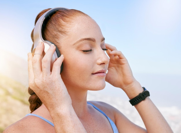 Woman music and zen podcast during meditation in nature relax and calm with blue sky views Radio wellness and yoga by girl enjoying a break with calming audio on a fitness workout alone in summer