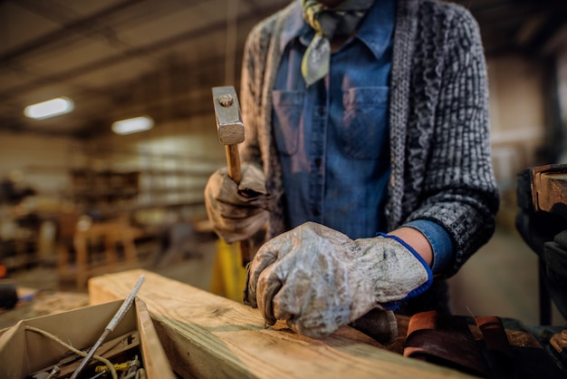 Woman nailing nails in carpentry workshop