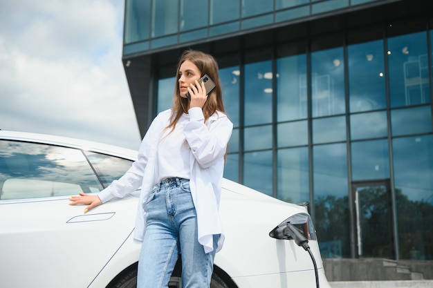 Woman near electric car Vehicle charged at the charging station