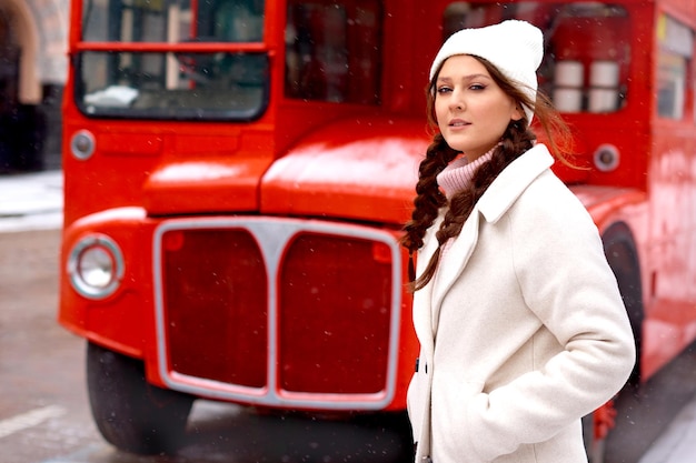 Woman near London double decker red old bus in winter walking in city in holidays