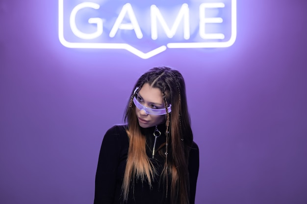 Woman in neon glasses in a neon room with neon game signs.