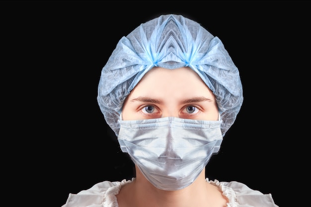 Woman nurse wearing medical mask and hat on black background. Protection from coronavirus infection, health care concept