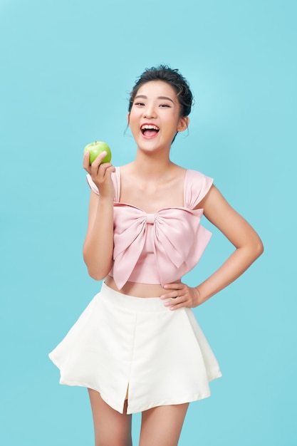 Woman opening her mouth bites an apple while holding it in her hands