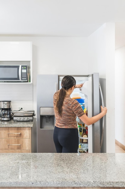 Woman opening refrigerator in kitchen