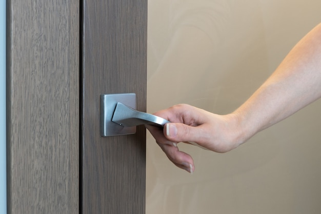 Woman opens or closes door. Closeup of hand opening door, unrecognizable person. Only hand is visible