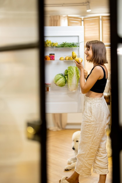 Woman opens fridge filled with healthy food ingredients