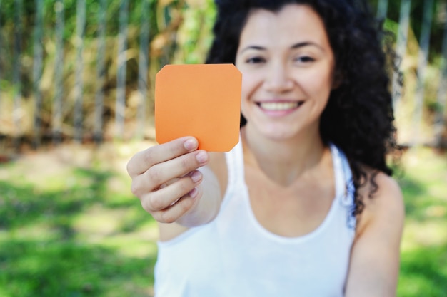 Woman outdoors showing a blank notepad.