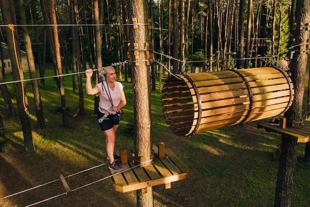 A woman overcomes an obstacle in a rope town A woman in a forest rope park