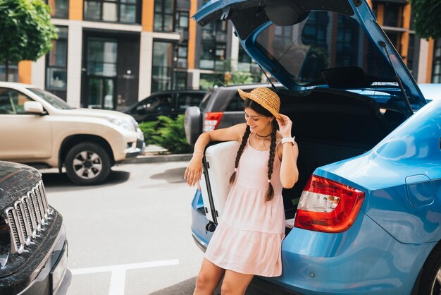 Woman packing her suitcase into luggage boot of the car