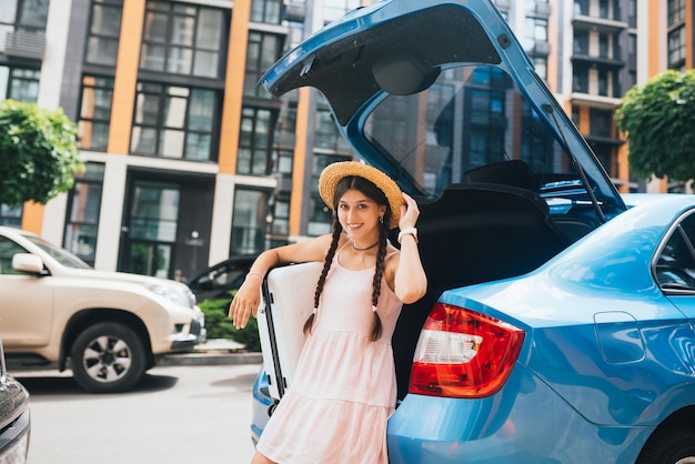 Woman packing her suitcase into luggage boot of the car