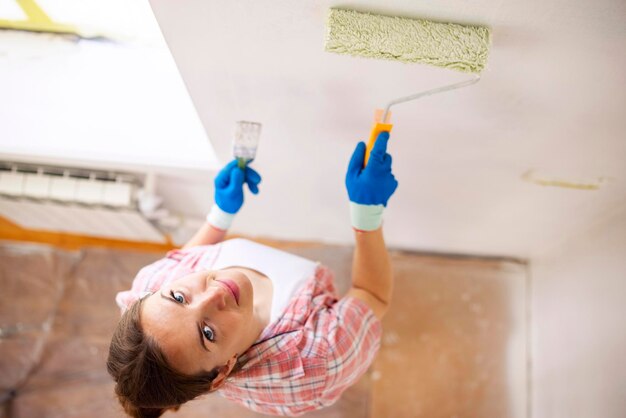 Woman painting wall with roller brush