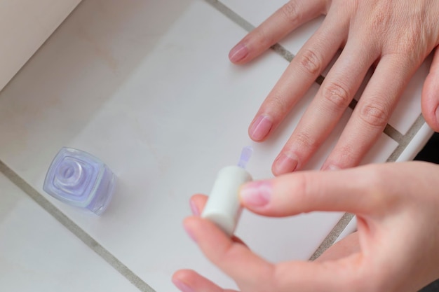 Woman paints her nails with transparent vegan nail polish Eco self care