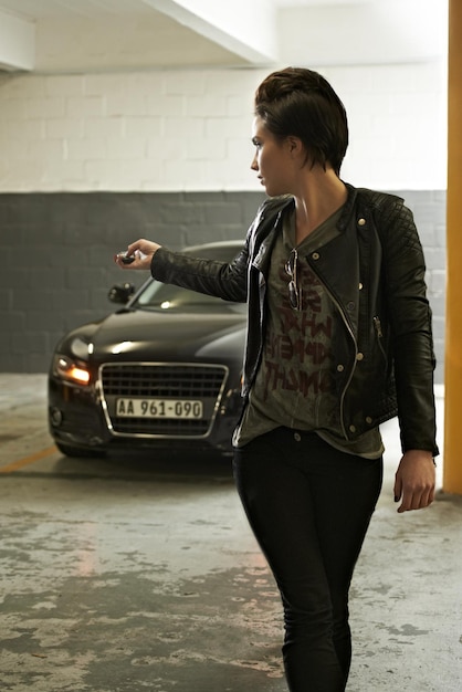 Woman parking and lock car with cool punk style in garage for safety at home Underground vehicle and female person with button for security with edgy fashion and driving trasnportation and trip