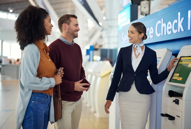 Woman passenger assistant and couple at airport by self service check in station for information help or FAQ Portrait of happy female services agent helping travelers register or book air flight