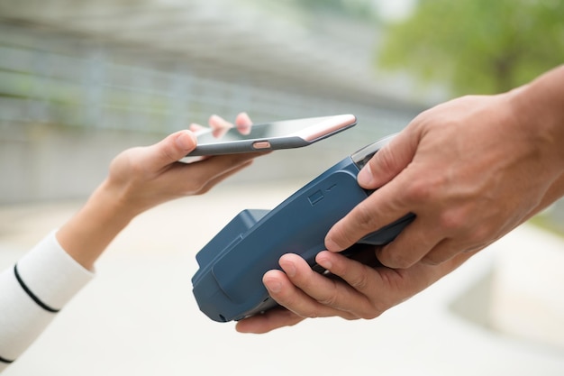 Woman pay by mobile phone with NFC technology at outdoor cafe