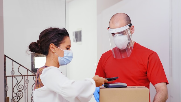 Woman paying using phone app for her for package delivery.