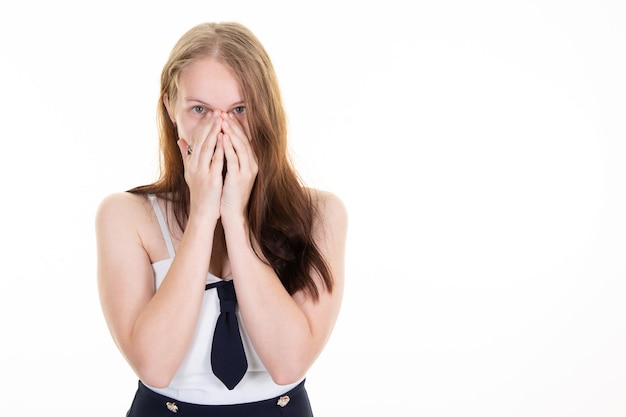 Woman peeks though fingers covers face woman with both hands in portrait frightened expression as notices something terrible scaring on copy space white background