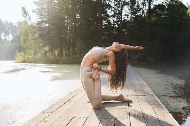 Woman performing Ushtrasana exercise with Virasana camel and hero pose exercising outdoors in park