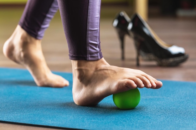 A woman performs relaxing exercises of the muscles of the foot with a massage ball