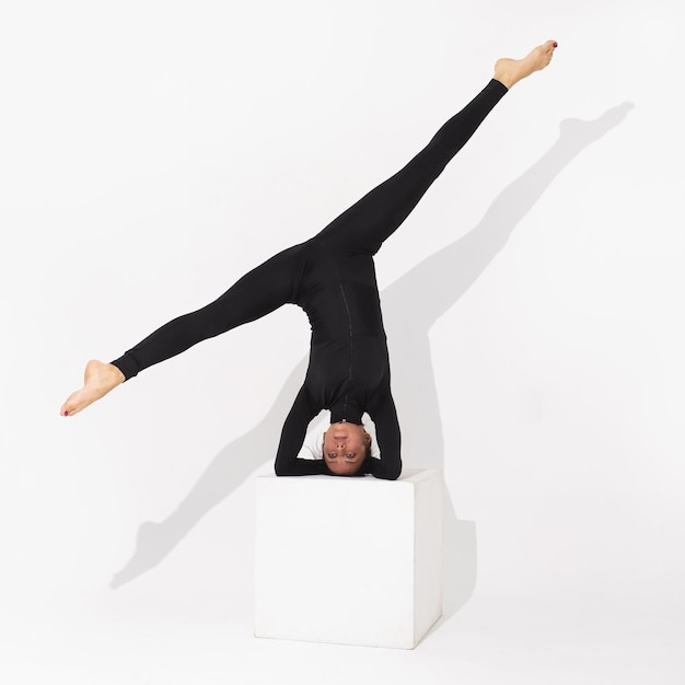 woman performs the Salamba Shirshasana exercise inverted asana pose or headstand stands on a cube