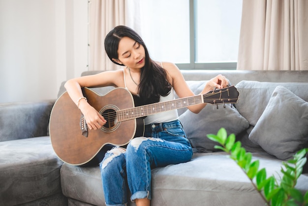 Woman person playing acoustic guitar music instrument at home young Asian musician girl lifestyle