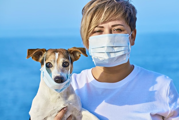 Woman and pet wearing face mask as virus protection concept