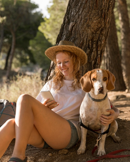 Woman petting her cute dog and using her mobile phone