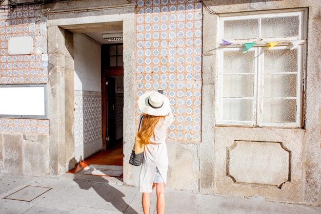 Woman photographing old building facade with portuguese tiles in Porto, Portugal