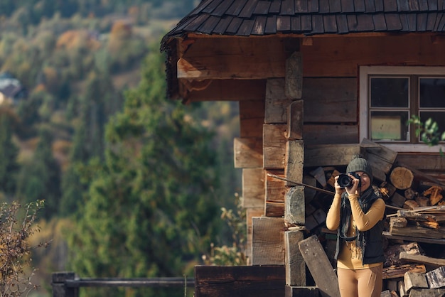 Woman photographs autumn mountain nature on DSLR camera.