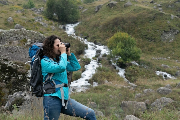 A woman photographs the landscape in the mountains.