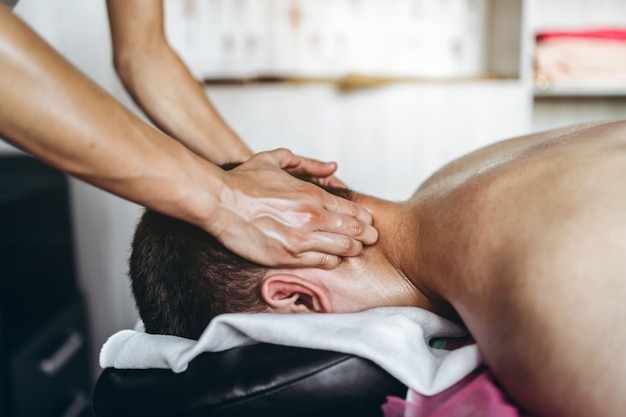 A woman physiotherapist doing neck massage for a man in the medical office. Closeup of hands doing massage